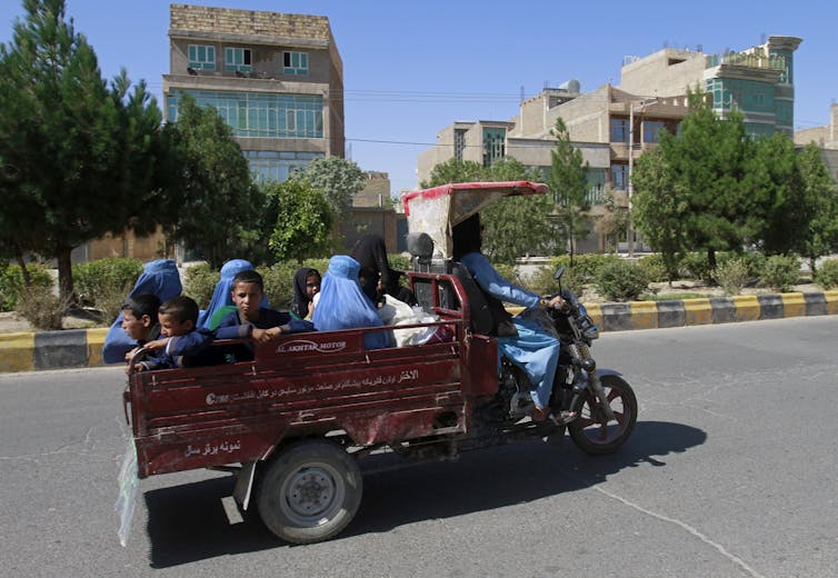 Afghan women and children travel in a motorcycle cart