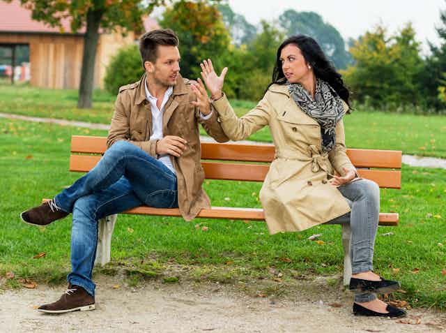 man and woman seated on bench having heated discussion