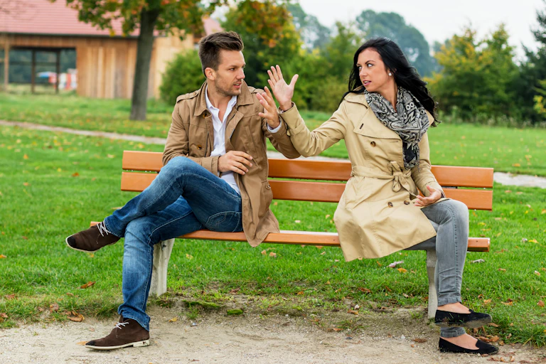 man and woman seated on bench having heated discussion