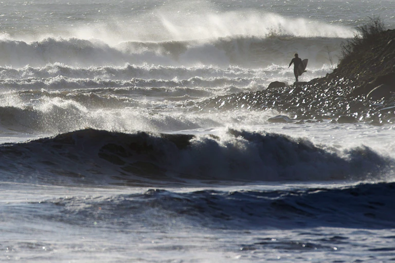 Un surfer se tient debout au milieu d'une mer déchaînée