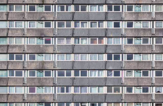 The facade of a council housing tower block in London, showing rows of gray concrete and windows