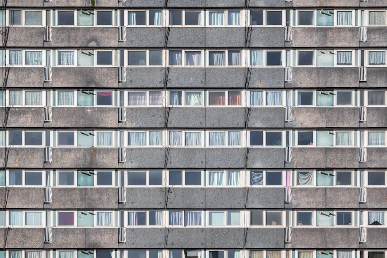 The facade of a council housing tower block in London, showing rows of gray concrete and windows