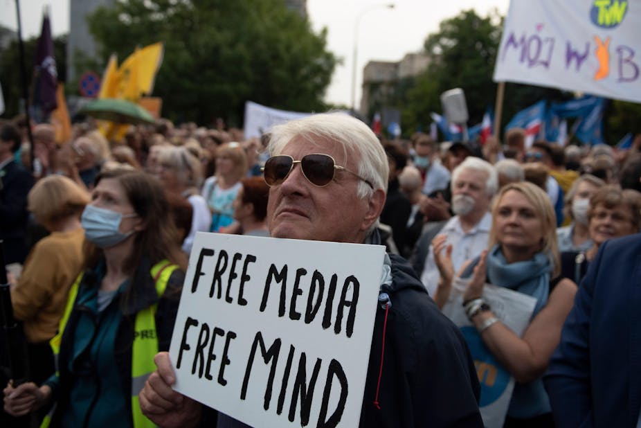 A man at a protest holding a sign reading 'free media, free mind'.