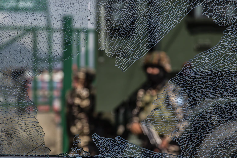 ndian government forces are seen through a broken glass of a vehicle