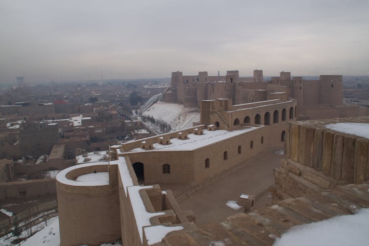 A large fortified building overlooks a city