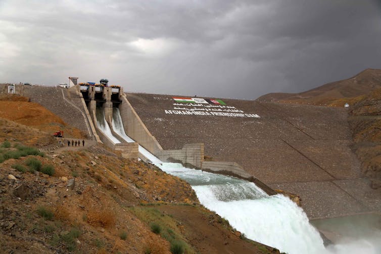 Water rushes from the bottom of a large dam