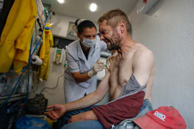 Man grimaces as he receives COVID-19 vaccine