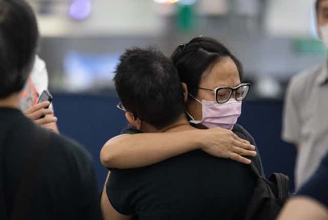 A woman hugs her friend as she departs, at Hong Kong international airport.
