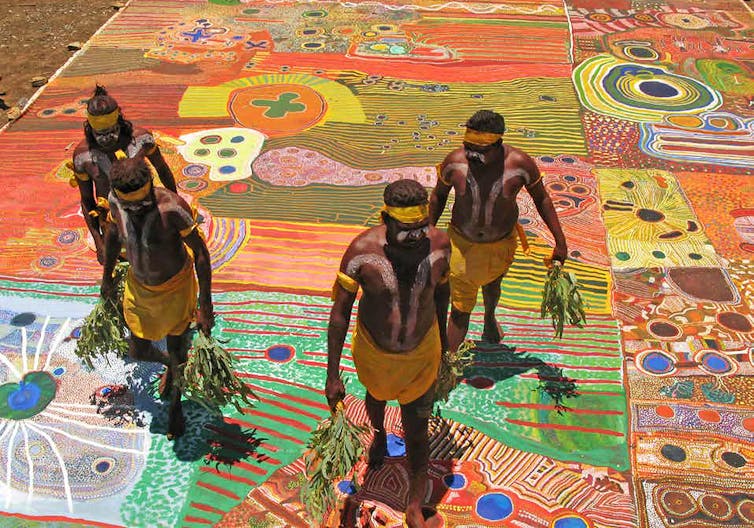 Indigenous dancers from WA's remote Kimberley region standing on the Ngurrara Canvas.