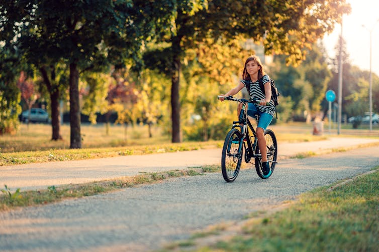 girl rides bike through park