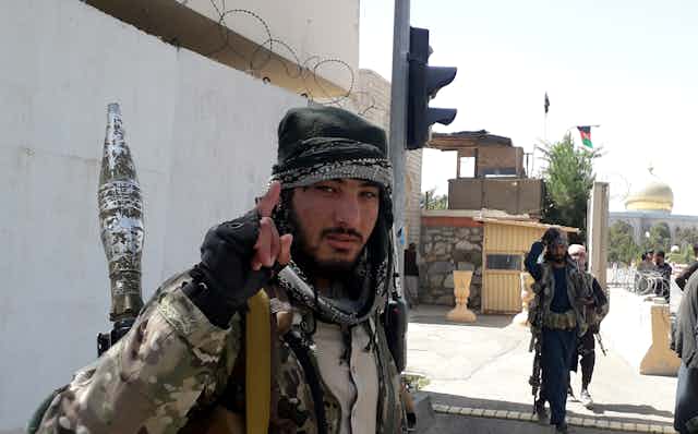 A Taliban militant looks toward the camera and holds up his index finger