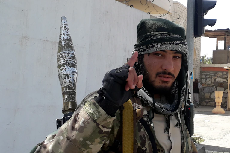 A Taliban militant looks toward the camera and holds up his index finger