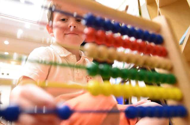 A boy plays with an abacus.