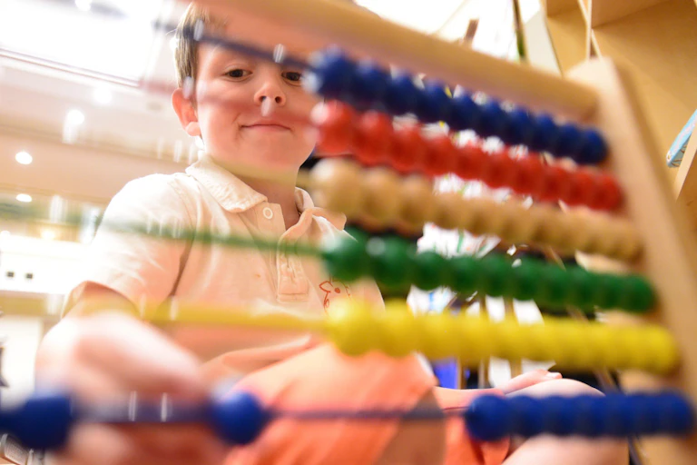 A boy plays with an abacus.