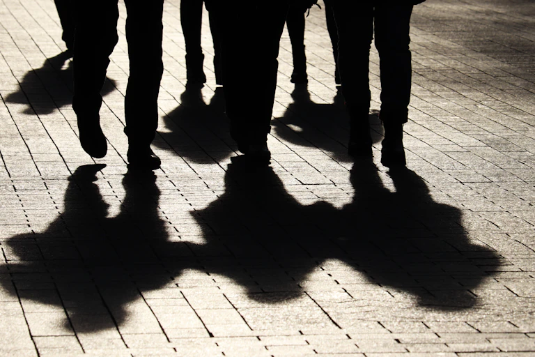 Shadows of three people cast on a brick sidewalk
