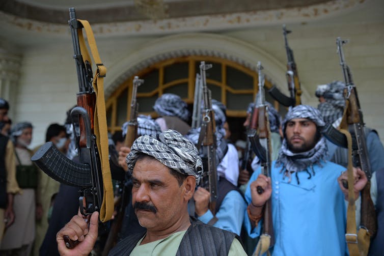 Men carrying rifles gather outside a building