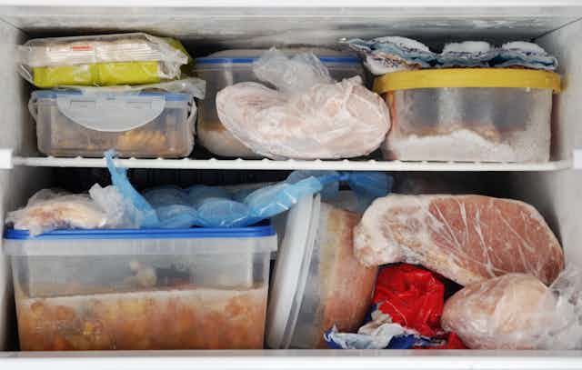 Frozen food inside a freezer. Lots of leftovers in plastic containers.