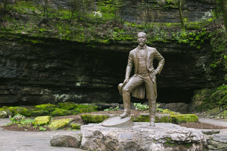 Statue of man in front of water.