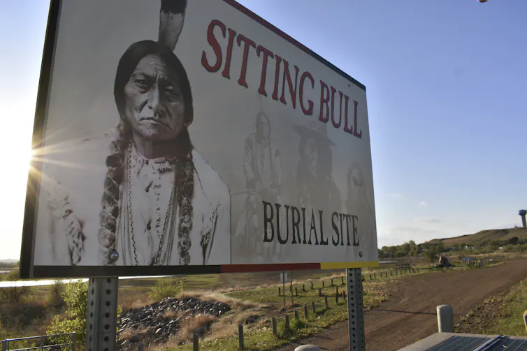 A billboard with a photo of Sitting Bull on it reads 'sitting bull burial site'