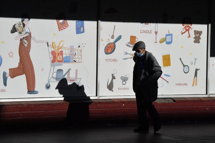 A man in a mask walks down an empty street.