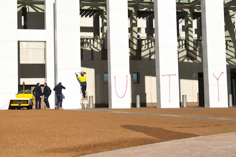 Climate change graffiti is cleaned off the walls of parliament house.