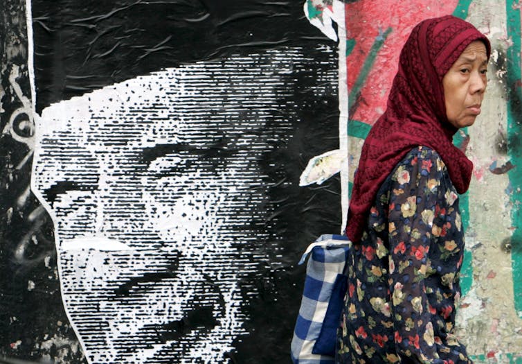 A woman walks past a poster of former president Soeharto in Jakarta.