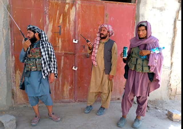 Tres combatientes talibanes hacen guardia en un puesto de control 