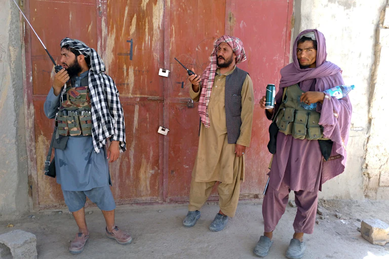 Tres combatientes talibanes hacen guardia en un puesto de control