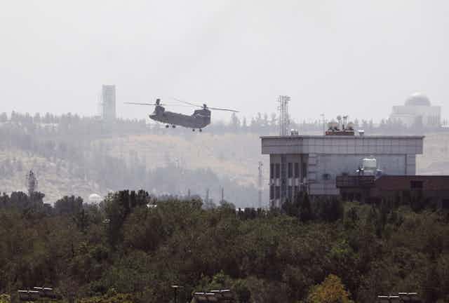 A U.S. Chinook helicopter flies near the U.S. Embassy in Kabul, Afghanistan, Sunday, Aug. 15, 2021. Helicopters are landing at the U.S. Embassy in Kabul as diplomatic vehicles leave the compound amid the Taliban advanced on the Afghan capital