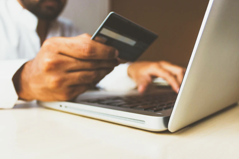 Hands holding a credit card and entering the number into a laptop