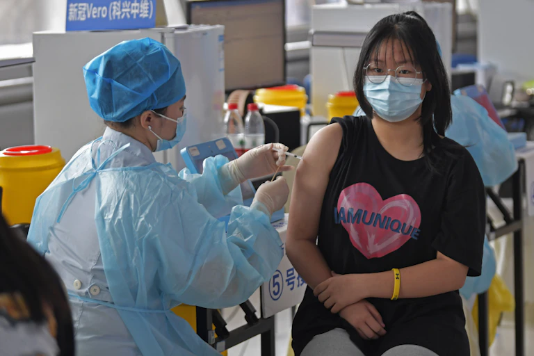 A nurse in PPE vaccinated a young woman in a mask.