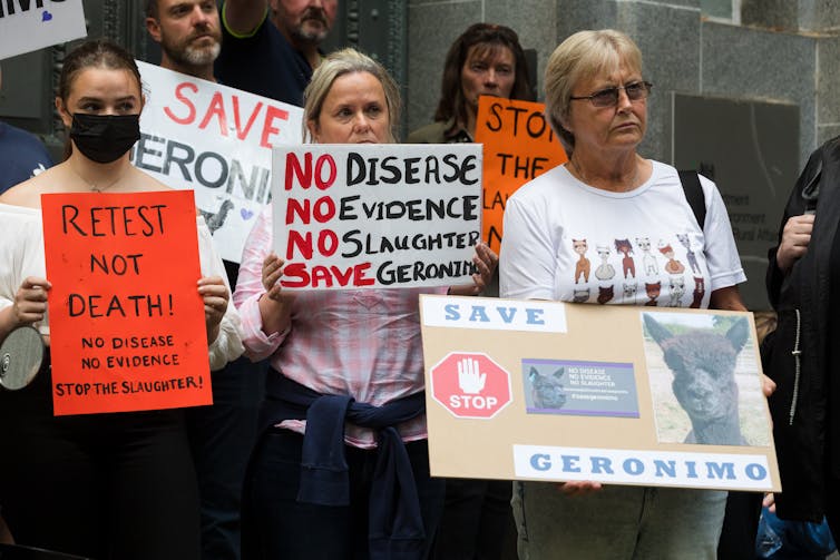 Demonstrators stand with signs protesting Geronimo's death sentence.