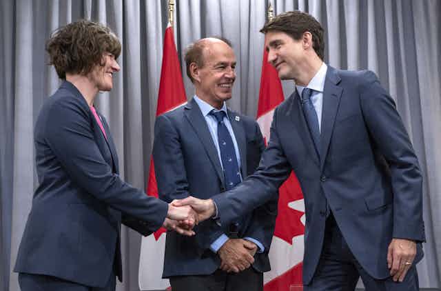 Justin Trudeau shakes hands with Megan Leslie as Marco Lambertini looks on. All three smile.