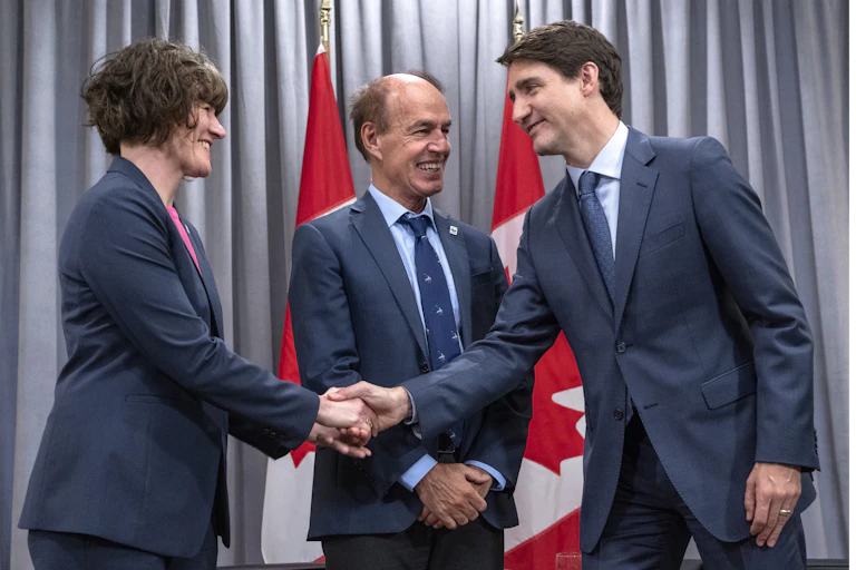 Justin Trudeau shakes hands with Megan Leslie as Marco Lambertini looks on. All three smile.