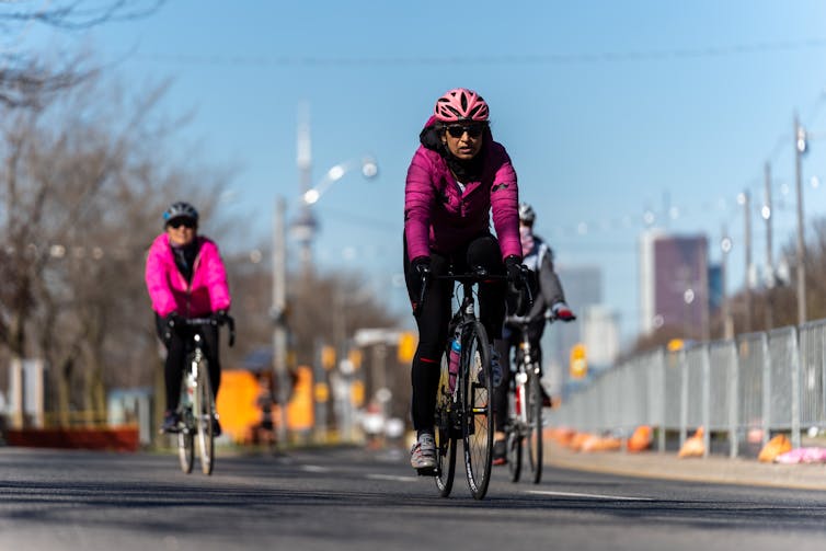 Three cyclists bike along a closed road downtown Toronto