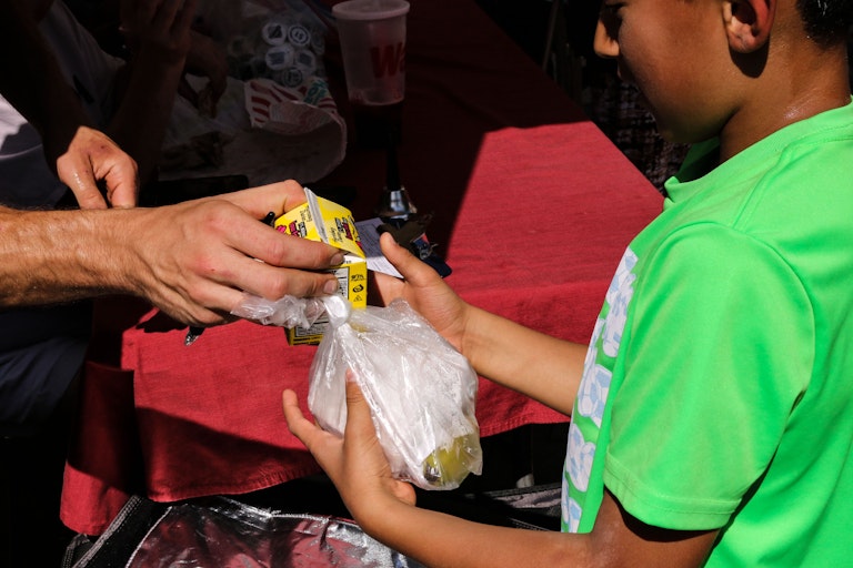 A school boy gets served lunch in a bag.