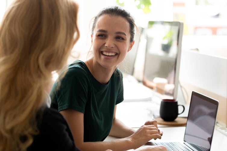 Young woman smiles as she gets advice from another woman