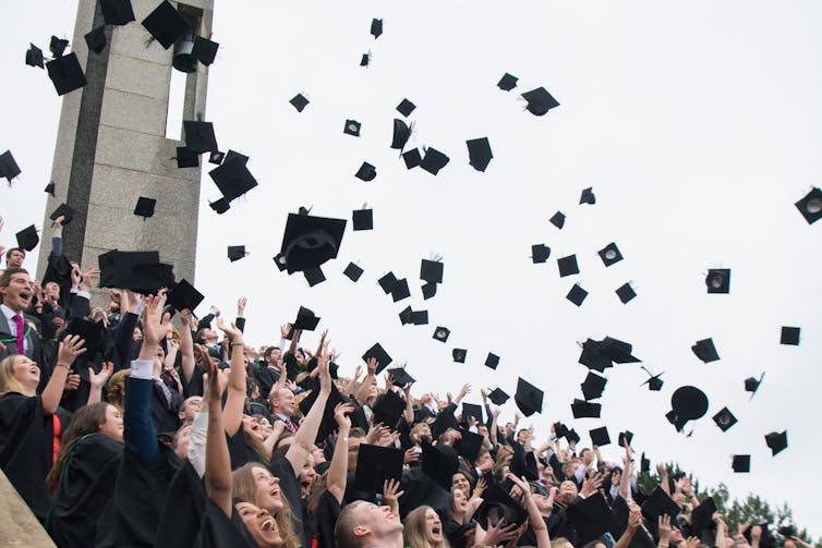 Students throw their black caps up into the air on graduation day