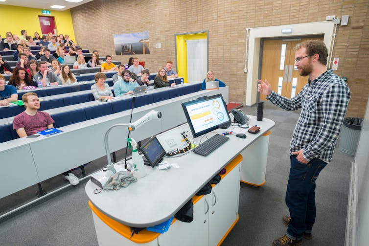 A lecturer leads a class in a university auditorium