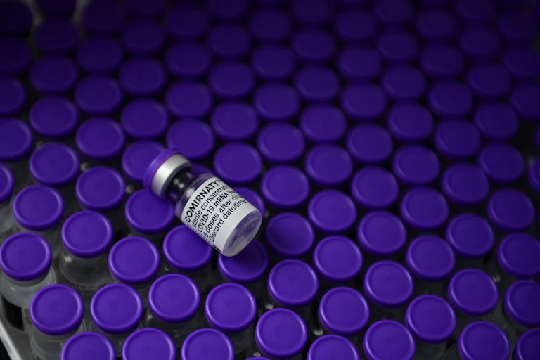 Une fiole du vaccin Pfizer (Comirnaty) est posée sur des dizaines d'autres.