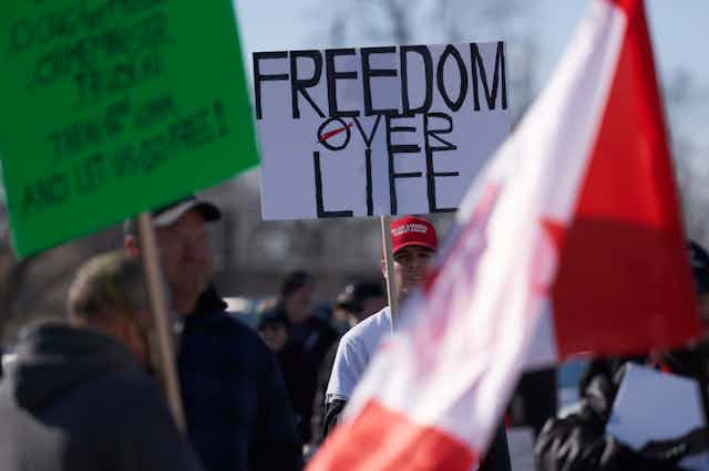 A man holds a Freedom over Life sign at an anti-mask protest.