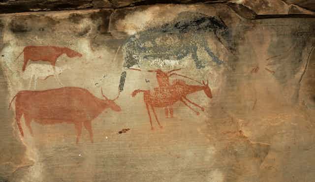 Rock art paintings of four animals, one a horse with the figure of a rider on the horse, holding a gun.