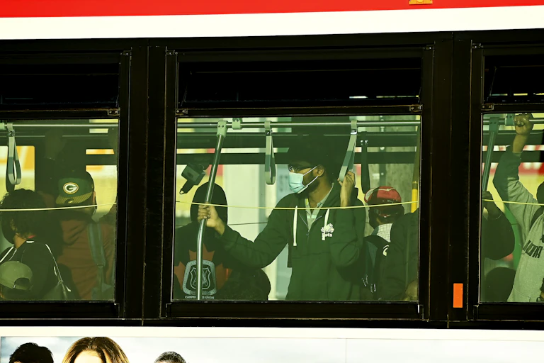 People are shoulder to shoulder inside a city bus while commuting at rush hour during COVID-19