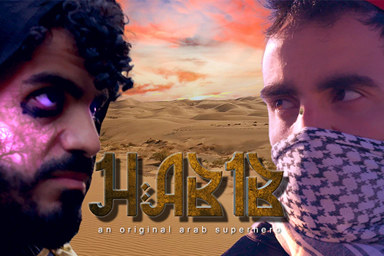 Two men facing each other against a desert backdrop, one with a keffiyah scarf around his mouth.