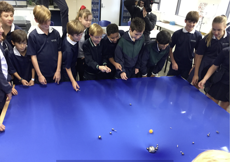 Students stand around a lycra surface simulating spacetime