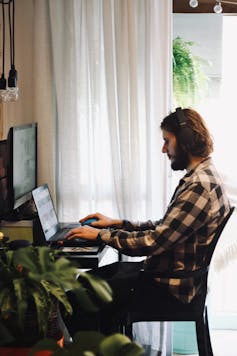 Man sits on computer at home work station.