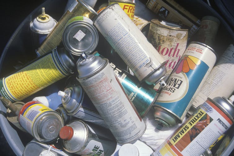 A bin full of discarded aerosol cans.