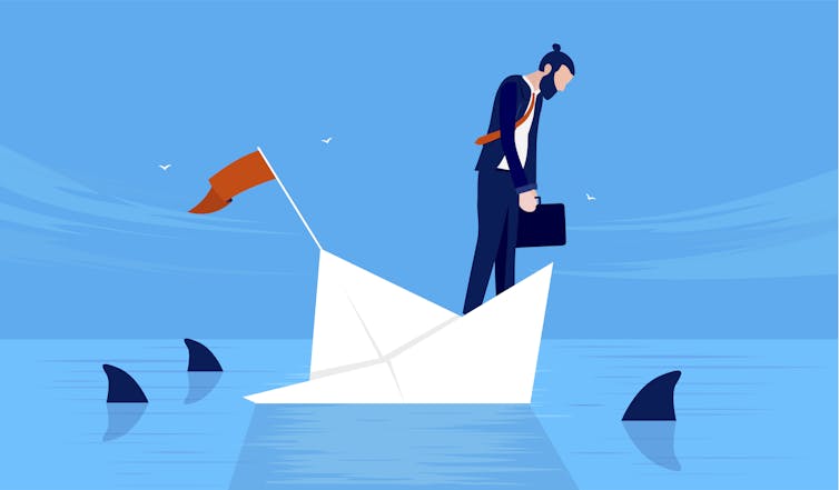 Businessman on sinking boat surrounded by sharks.
