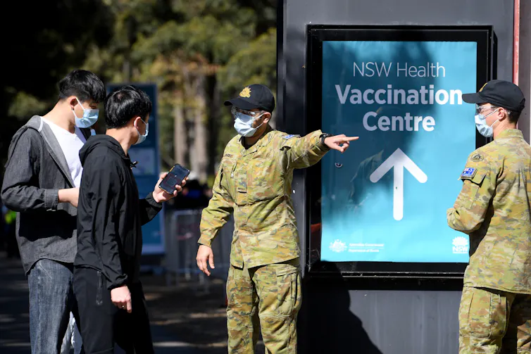 People being directed to a vaccination centre by men in army fatigues