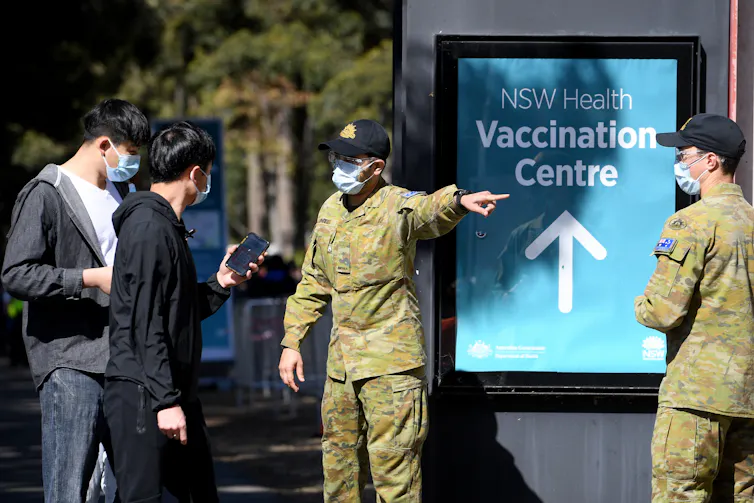 People being directed to a vaccination centre by men in army fatigues